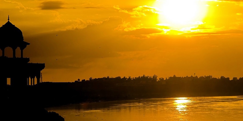 A sunset view of a beautiful lake with a tomb on the side.