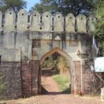 Manikgad Fort lies on a hill in Maharashtra, showing its old ruins and rough landscape.