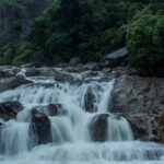 A breathtaking view of Manimuthar Waterfalls cascading down amidst lush greenery.