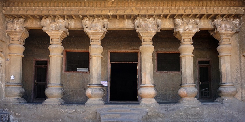 Ancient facade of a cave near Maharashtra showcasing rock-cut architecture with carved pillars.