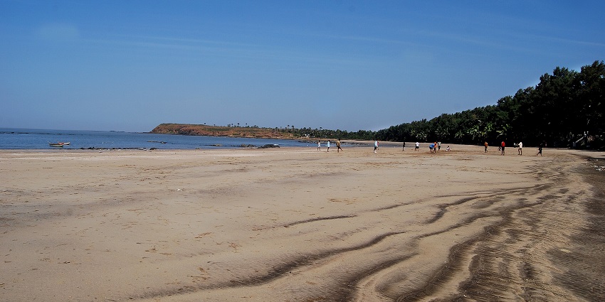 View of Manori Beach with people walking along the shore and a boat near the waterline