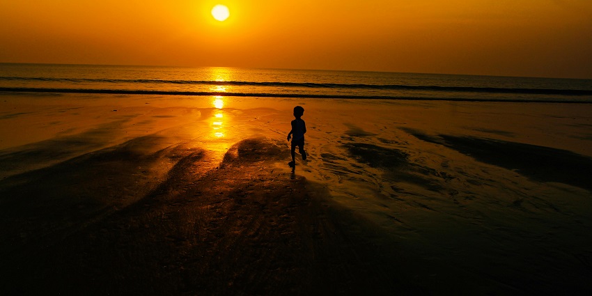 A silhouette of a child running towards the sea near a beach in Mumbai, Maharashtra.