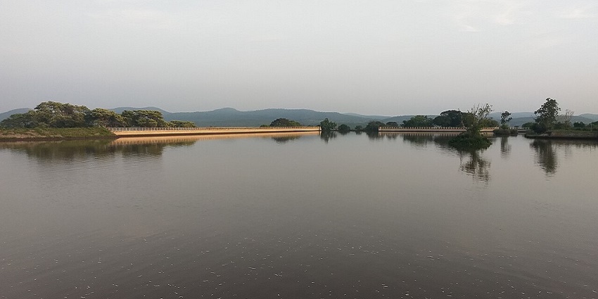 A scenic view of Maravakandy Dam surrounded by lush greenery and majestic hills.