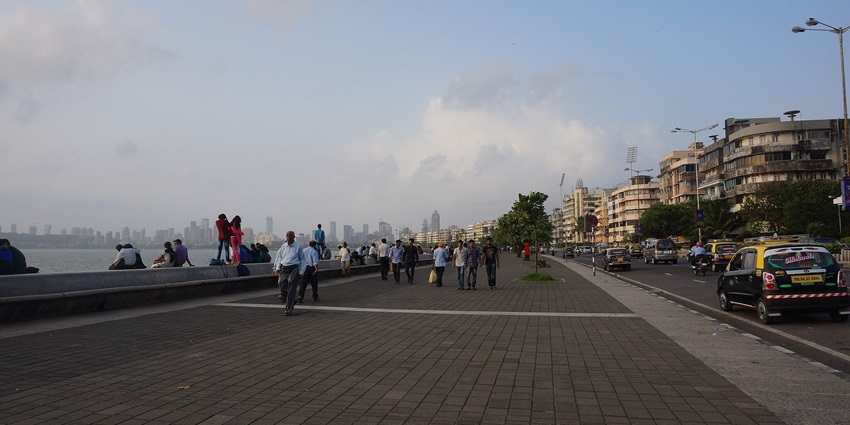 View of people walking across the Marine Drive with Arabian Sea views and lights