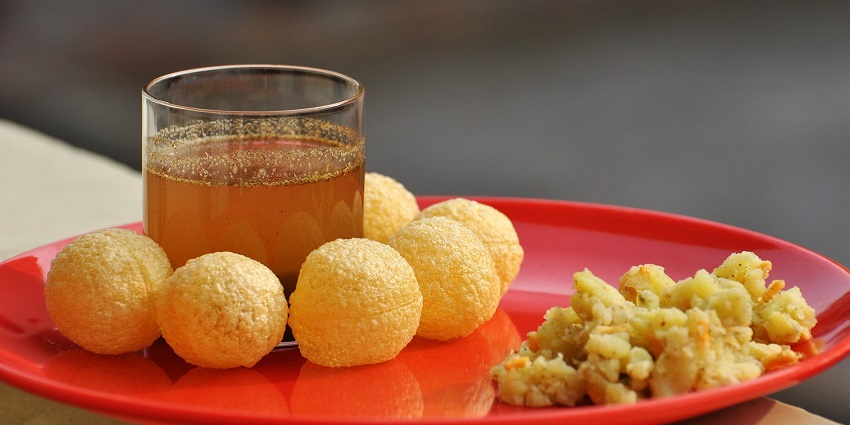 Panipuri, an Indian chaat, served with mashed potato and bean filling and flavoured water