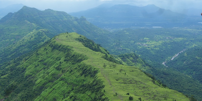 An aerial view of a plateau in Matheran with lush green mountains in the background