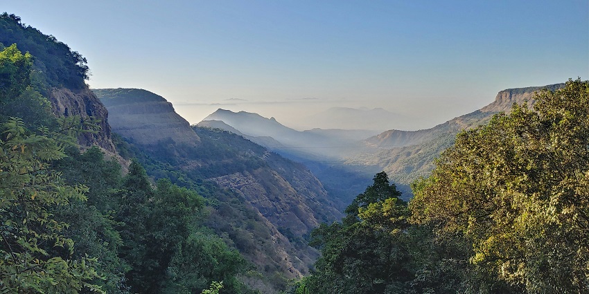 A view of a waterfall cascading down rocky cliffs surrounded by greenery in Matheran.