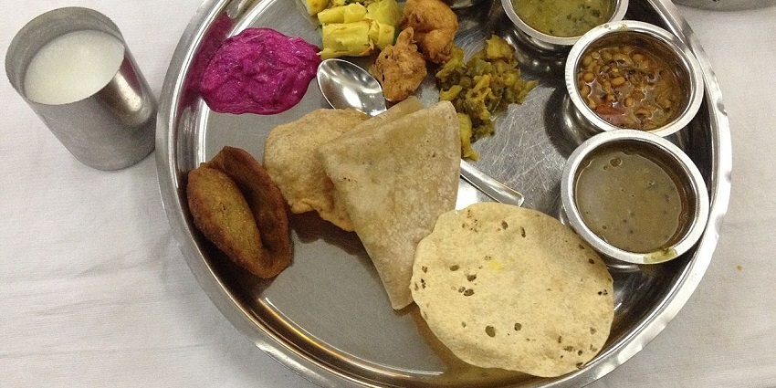 Maharashtrian Veg thali with roti dal, veggies, sol kadhi and papad on a steel plate.