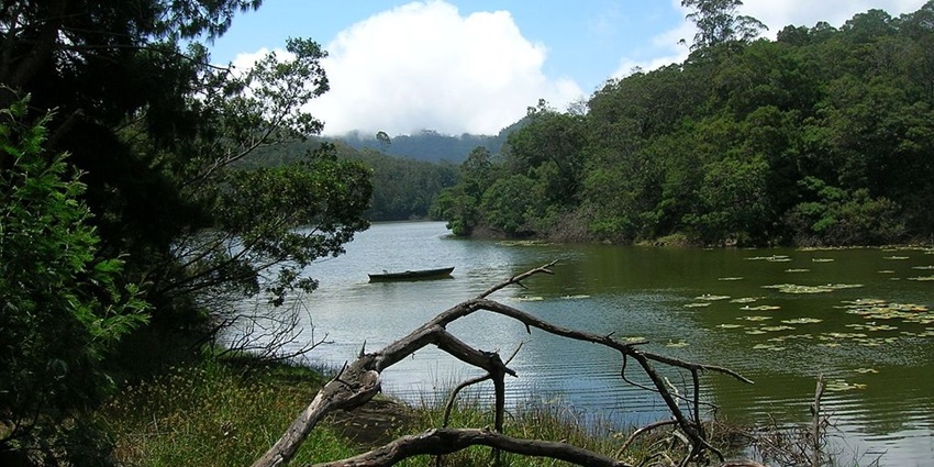 Berijam Lake, surrounded by green hills and a forested area on a clear day.