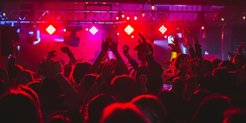 Image of a club night party view with vibrant red lights and people dancing on the floor