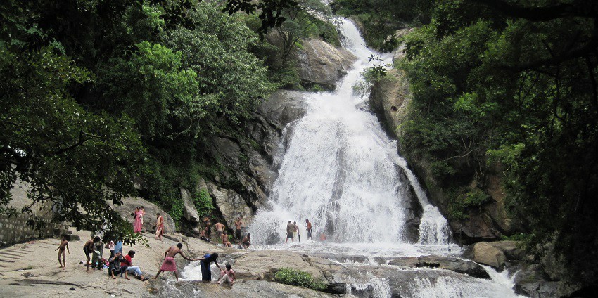 View of Monkey Falls, beautiful waterfalls in Tamil Nadu, flowing through rocks and grass.