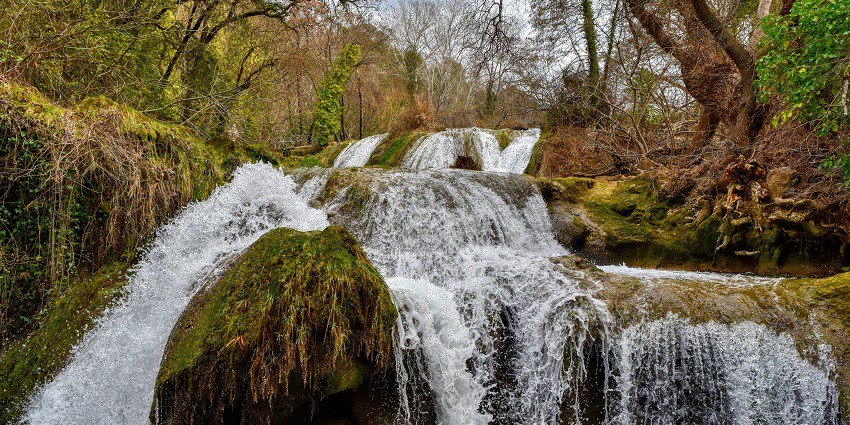 A glimpse of water cascading through the rocky terrains and surrounded by greenery.