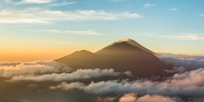 Panoramic view of sunrise at Mount Batur with surrounding lake, morning sky and clouds.