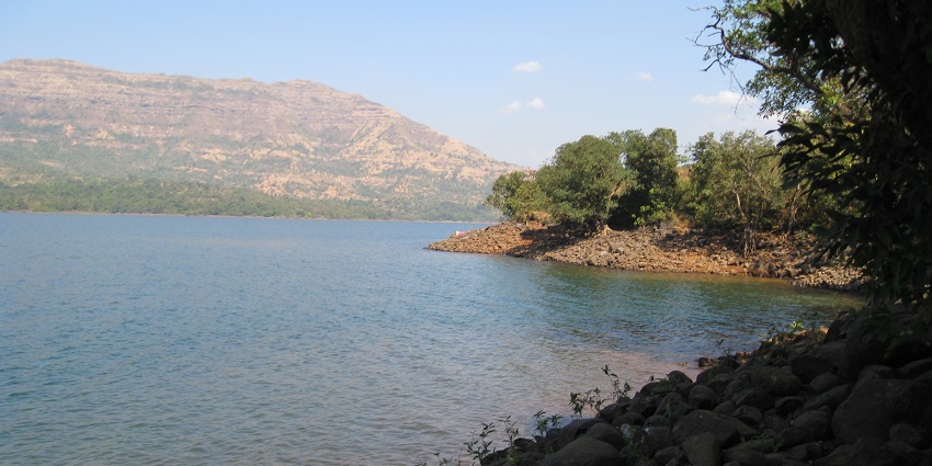 Mulshi Lake with calm waters surrounded by green hills and trees along the shoreline