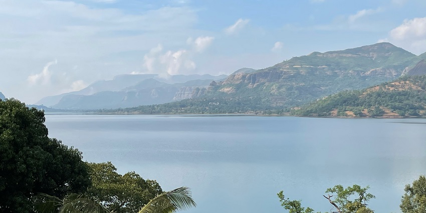 A scenic view of Mulshi Lake in Pune with lush greenery and hills surrounding it.