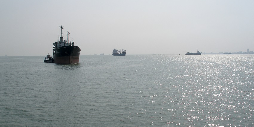 Ships in Mumbai Harbour with a distant view of the famous place near Elephanta Caves.