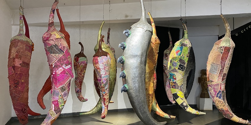 Colourful hanging art installations shaped like pods or chillies in a modern gallery.