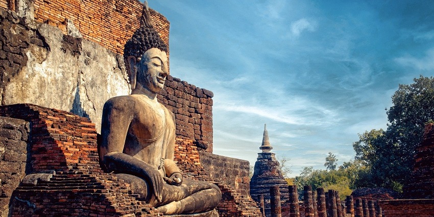 A majestic Buddha statue surrounded by temple ruins, evoking quiet and peace.
