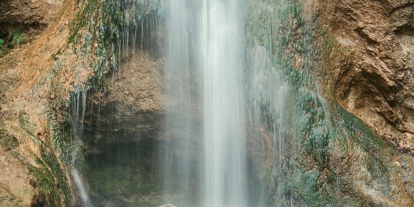 Restful waterfall cascading into a clear pool, surrounded by vegetation and rocks.