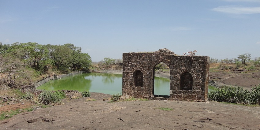 The picture of the historical fort ruins at Narnala with parts of a wall beside a lake.