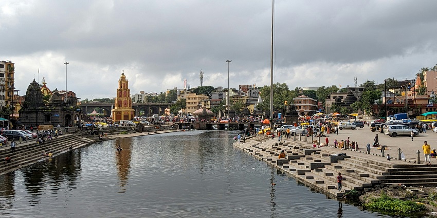 A scenic view of a ghat, shimmering waters, and iconic temples of Nashik, Maharashtra.