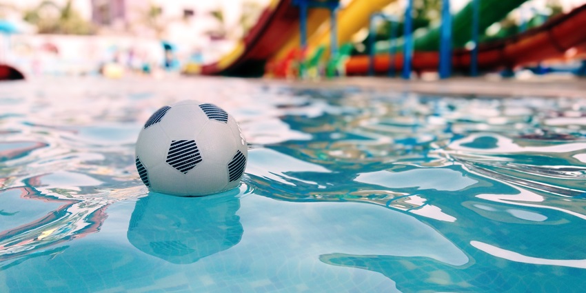 View of a football lying in the swimming pool at one of the theme parks with a blurred background of slides