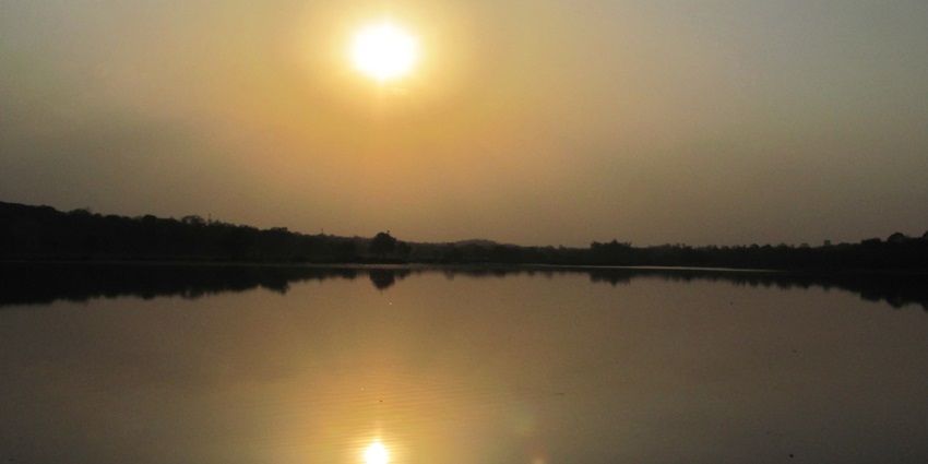 A serene sunset over a lake, reflecting vibrant orange and pink hues.