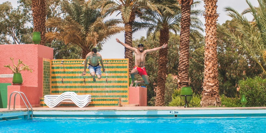 A diving into a pool surrounded by trees, enjoying a summer day in a water park