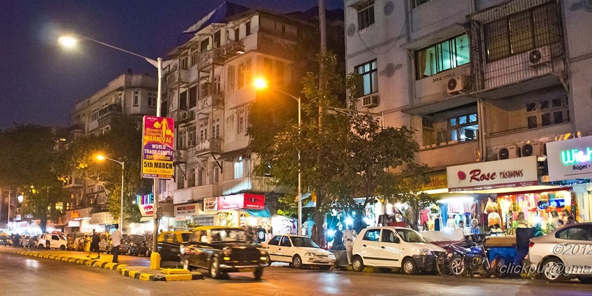 Busy street scene at Colaba in Mumbai, with a variety of shops in the background.