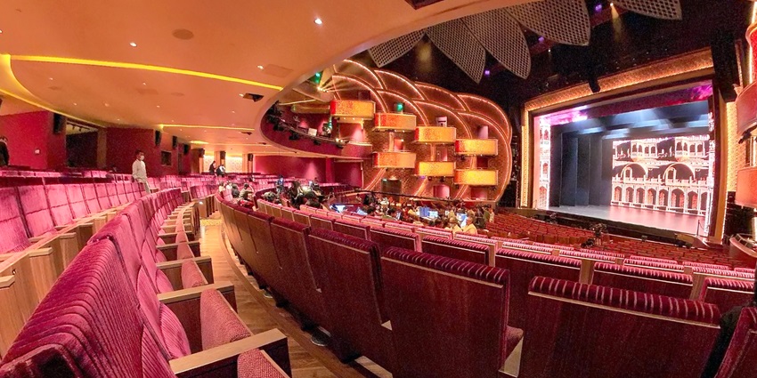 Nita Mukesh Ambani Cultural Centre auditorium with plush red seating and an ornate stage.