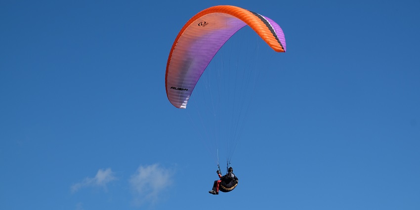 A thrilling view of paragliding in Ladakh with scenic cliffs and blue skies.