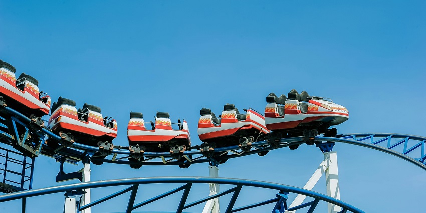 A photo of a red and white roller coaster with steep curves.