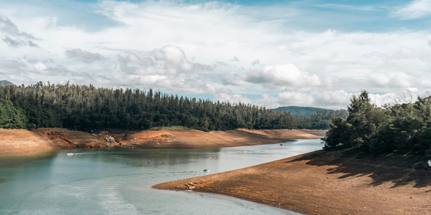 A breathtaking vista of Ooty featuring tall green-capped mountains and azure waters.