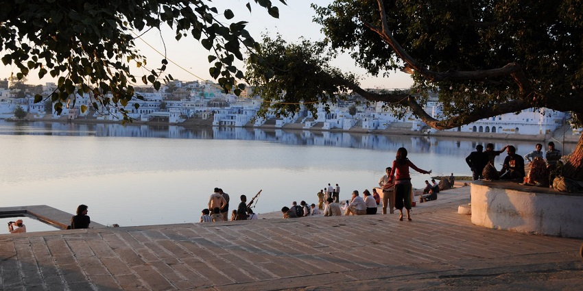 Tourists enjoying the sunset at Fateh Sagar Lake with colourful sky reflecting on the water.