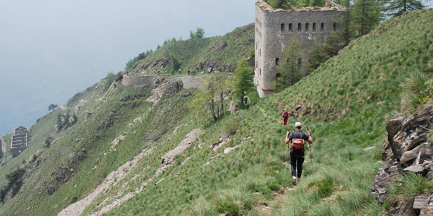 Image of a person walking through green hills to the ancient fort during day time view