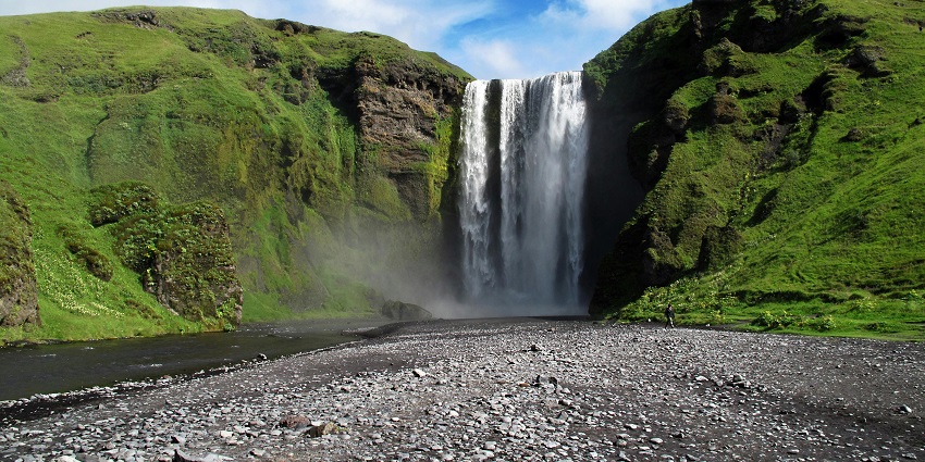 The stunning Khandi Waterfalls flowing gracefully in a lush green landscape during the daytime.