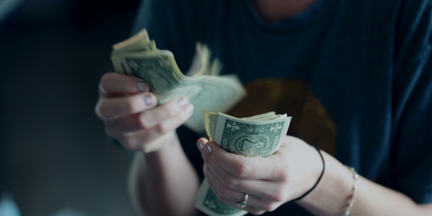An image showing a person counting money, to make a payment at a cafe in Dreamland Beach.