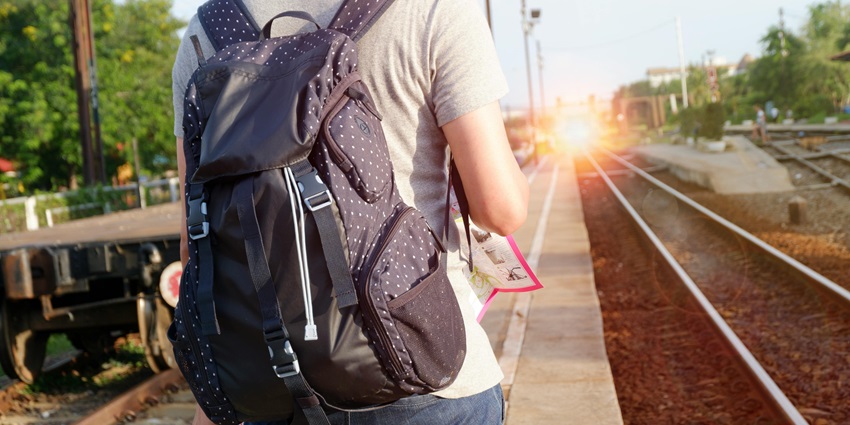 An image of a person with a backpack waiting for a train at a platform near Istiqlal Mosque.
