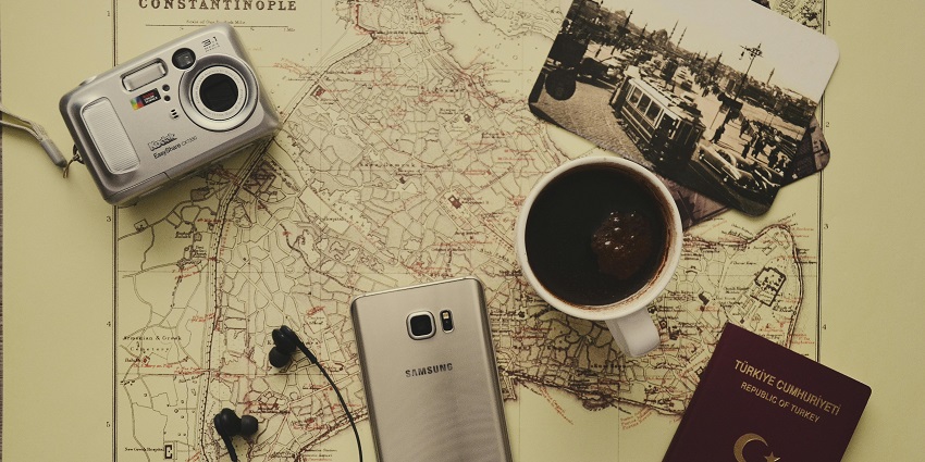 A notebook, phone, earphones and much more displayed on a map over a table.