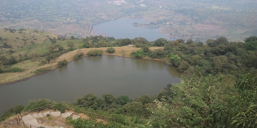 An aerial picture of a mountain with a lake in front of it, surrounded by greenery