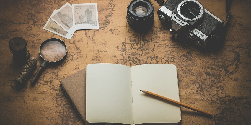 An image of travel things for Harishchandra Fort - a camera, a dairy and a magnifying lens.