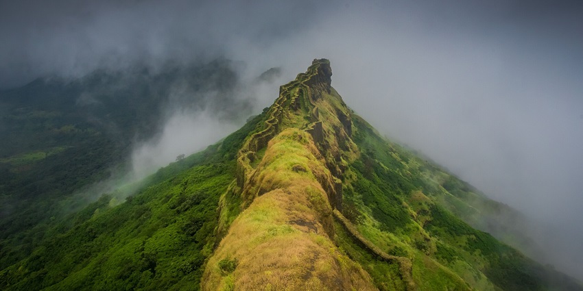 A scenic view of Suvela Machi at Rajgad Fort, featuring rugged cliffs and green valleys.