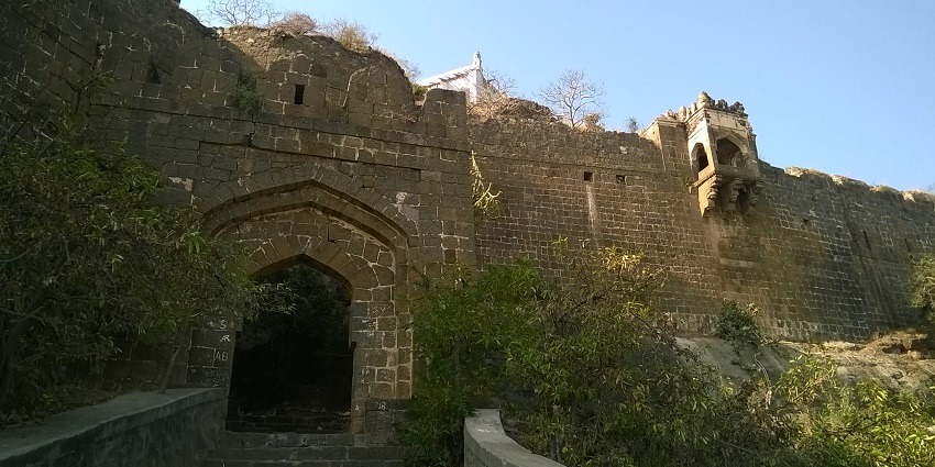 View of an archway gate of the building surrounded by shrubs