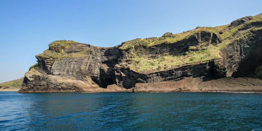 A breathtaking view from a cave overlooking a lake surrounded with vibrant greenery