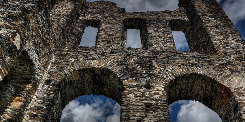 The Morgiri Fort is an ancient castle ruins with stone walls and arches set against a cloudy sky.