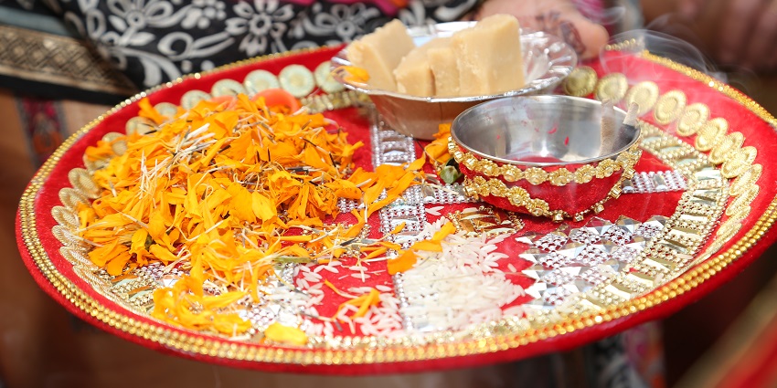 Image of a pooja thali for doing all the rituals and aarti with flower decoration and sweets as prasad