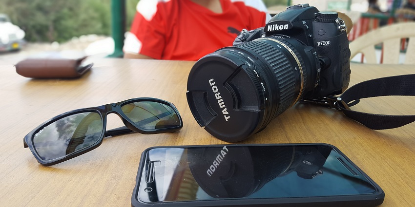 Image of phone, sunglasses and a black camera to capture views on your trip
