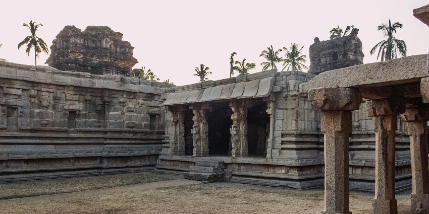 An ancient Indian temple with intricate stone carvings, surrounded by lush greenery.