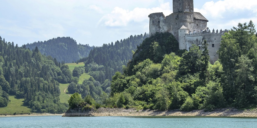 Calm waters are embraced by vibrant greenery, reflecting the charm of Hasdar Fort.