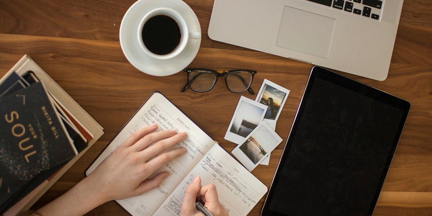 An image of travel things - a camera, a diary, a magnifying lens and many more.